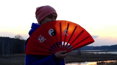 Beautiful Woman is Waving With Her Handheld Fan Back and Forth Outdoors on the Stock Footage