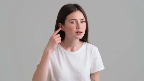 A beautiful woman wearing basic T-shirt is showing that she can't hear  Video stock 154947424