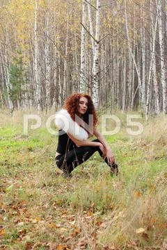 Beautiful woman with white fur poses in beautiful autumn forest at sunny day Stock Photos