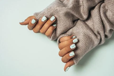 Beautiful women's hands with colored manicure, dressed in a warm wool sweater Stock Photos