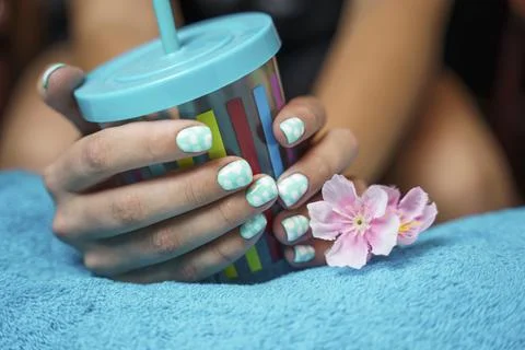 Beautiful women's hands with colored manicure hold a multicolored cup with a  Foto stock