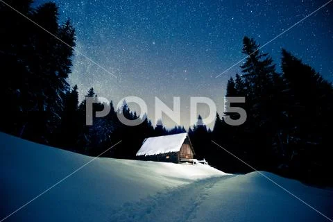 Beautiful wooden house in the winter forest under the stars Stock Photos