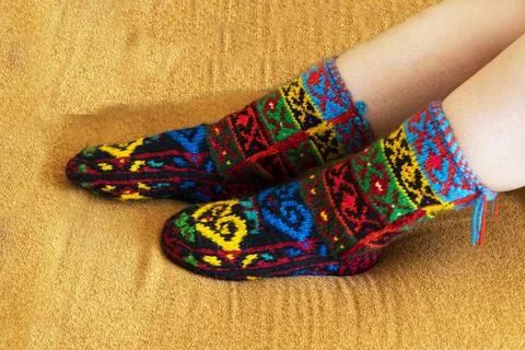 Beautiful wool socks made of multicolored threads on the girls feet Stock Photos