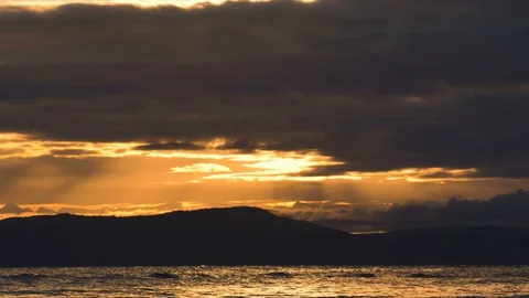 Beautiful yellow clouds with sun rays over ocean with birds flying Stock Footage 128407969