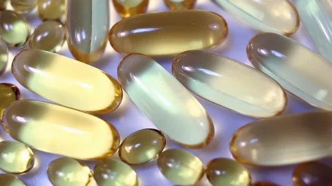 Beautiful yellow oval contrasting capsules large and small rotate on a purple ba Stock Footage 145107343