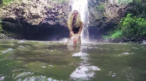 Beautiful Young Bikini Model Splashing Water at Camera in Lush Jungle Pond in Stock Footage 55356929