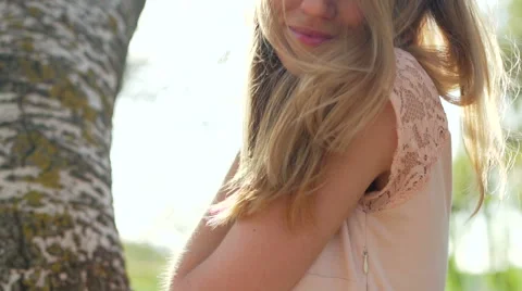 Beautiful young blode sitting on a tree among planting.  Stock-Footage 66442099