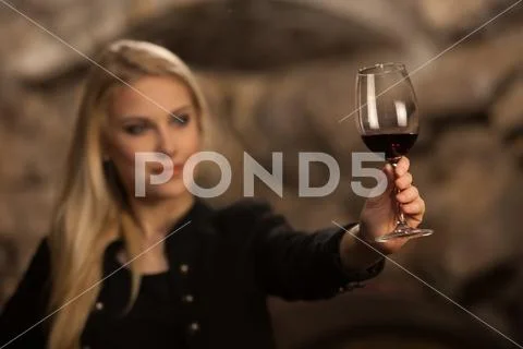 Beautiful young blond woman drinks wine in wine cellar Stock Photos
