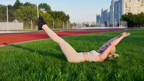 Beautiful young blonde doing abs exercise with raising her legs Video stock 138736646