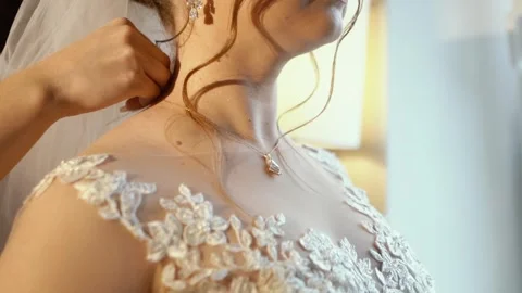 A beautiful young bride with a bare open neckline hangs a pearl jewelry on her Stock Footage 270950521