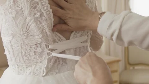 Beautiful young bride getting her dress tied on her wedding day everyone is very Stock Footage 306144791