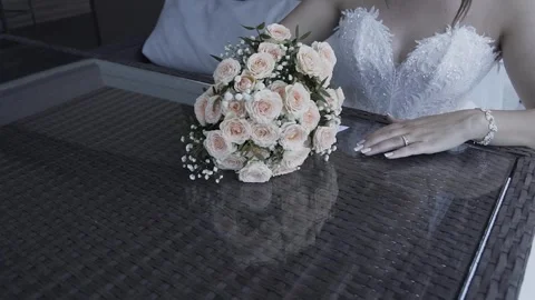 A beautiful young bride sits at a table and puts a wedding bouquet on the table Video stock 306146217