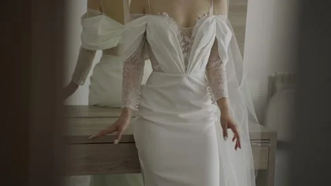 A beautiful young bride stands by the window in a stylish wedding dress 库存影片 329248511