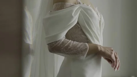 A beautiful young bride stands by the window in a stylish wedding dress 스톡 동영상 329248544