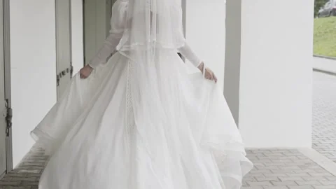 Beautiful young bride walking down the street her white dress fluttering in the Stock Footage 306145310