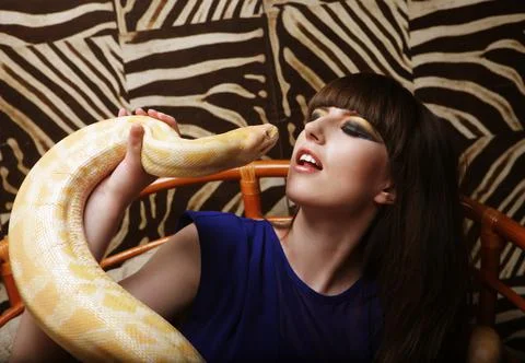 Beautiful young brunette holding a python and kissing him 写真素材