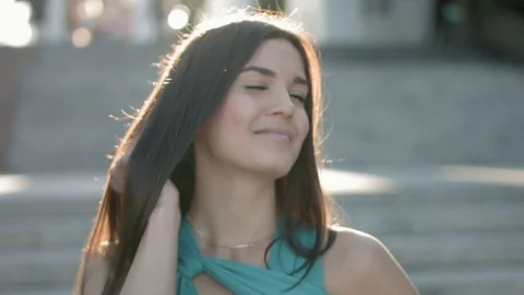 Beautiful young brunette in the rays of the setting sun waving to someone on the Stock Footage 78592737