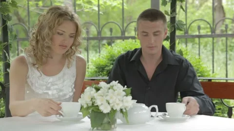 Beautiful young couple drinking tea from white cups in summer cafe Stock Footage 7766932