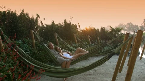 Beautiful young couple in a hammock in the sunset Stock Footage 87514698