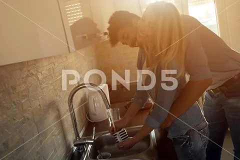 Beautiful young couple hugging and drinking coffee in kitchen Stock Photos