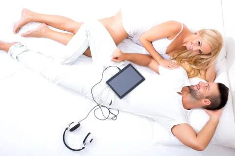 Beautiful young couple using a Tablet PC in Bed Stock Photos