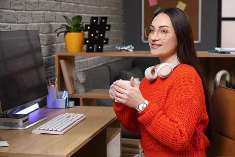 Beautiful young female programmer with cup of coffee at her workspace in mode Stock-Fotos