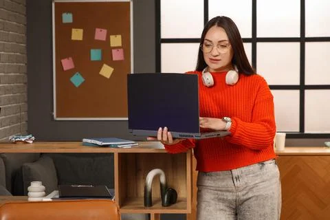 Beautiful young female programmer with laptop in modern office Stock Photos