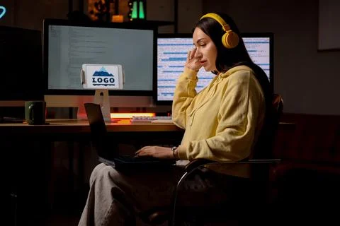 Beautiful young female programmer working with laptop in modern office at nig Stock Photos