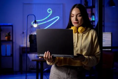Beautiful young female programmer working with laptop in modern office at nig Stock Photos