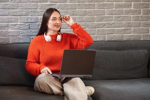 Beautiful young female programmer working with laptop on sofa in modern offic Stock Photos