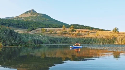 Beautiful young female training her yoga skills on a sup board Stock Footage
