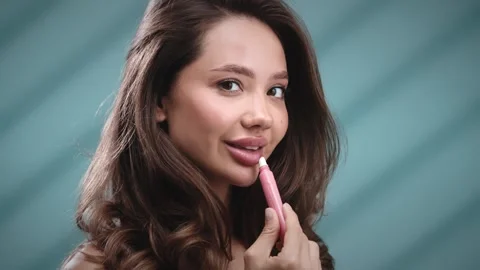 Beautiful young female using lip balm Stock Footage 331040367