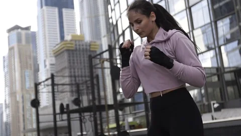 Beautiful young girl boxer dynamically trains punches, boxing on the roof of a Stock Footage 120112889