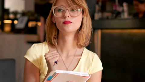 Beautiful young girl making notes in cafe in the city Stock Footage 113868096