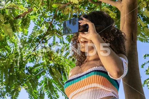 A beautiful young girl plays a game wearing virtual reality glasses on the pa Stock Photos