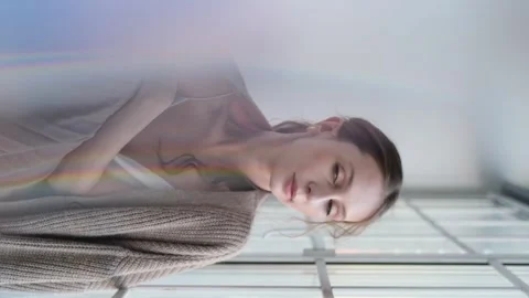 Beautiful young girl posing for the camera while sitting near a large window Stock Footage 273080692