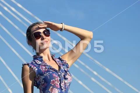 Beautiful young girl in sunglasses with her hand raised looking at the sun. Stock Photos