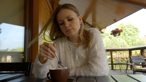 Beautiful young girl in white eats foam from coffee in a spoon Stock Footage 129952663