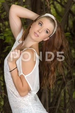 Beautiful young girl with white top and short pants standing in a bush Stock Photos