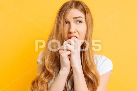 Beautiful young girl is worried, a woman with a terrified face, on a yellow b Stock Photos