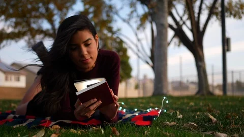 A beautiful young hispanic woman opening the pages of a story book or Stock Footage
