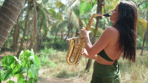 A beautiful young lady performs in a long green outfit and plays the saxophone. Stock Footage 234022500