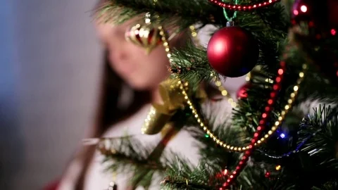 Beautiful young lady sitting on a chair near Christmas tree and reading a book. Stock Footage
