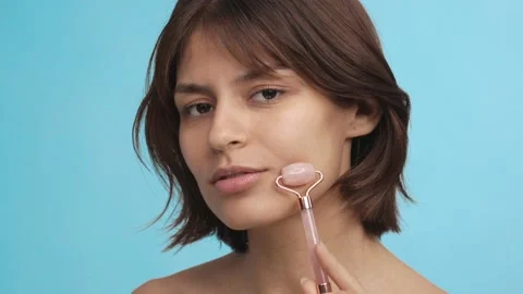 The beautiful young lady uses the quart role on her face. Facial treatment Video stock 233081432