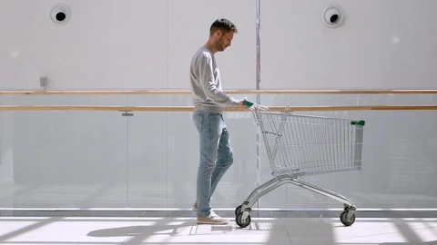 Beautiful young man having fun riding on shopping cart at supermarket. Stock Footage 127151133