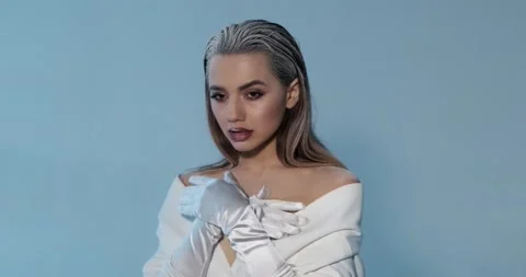 Beautiful young model poses for camera in photo studio, folds hands, looks up Stock Footage 130781764