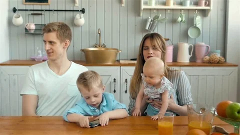 Beautiful young parents and their children smiling on kitchen breakfast at home Stock Footage