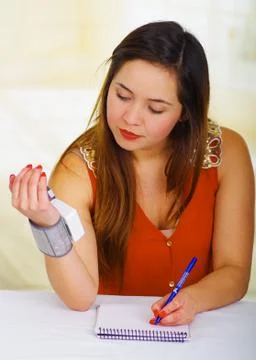 Beautiful young patient using an automatic tensiometer in her arm and taking 스톡 사진