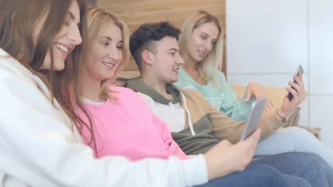 Beautiful young people are using smartphones and smiling while sitting on the Stock Footage 126210880