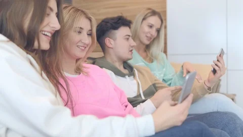 Beautiful young people are using smartphones and smiling while sitting on the Stock Footage 126212005